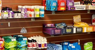 Various cannabis infused edibles in packs hanging on the shelves at a dispensary